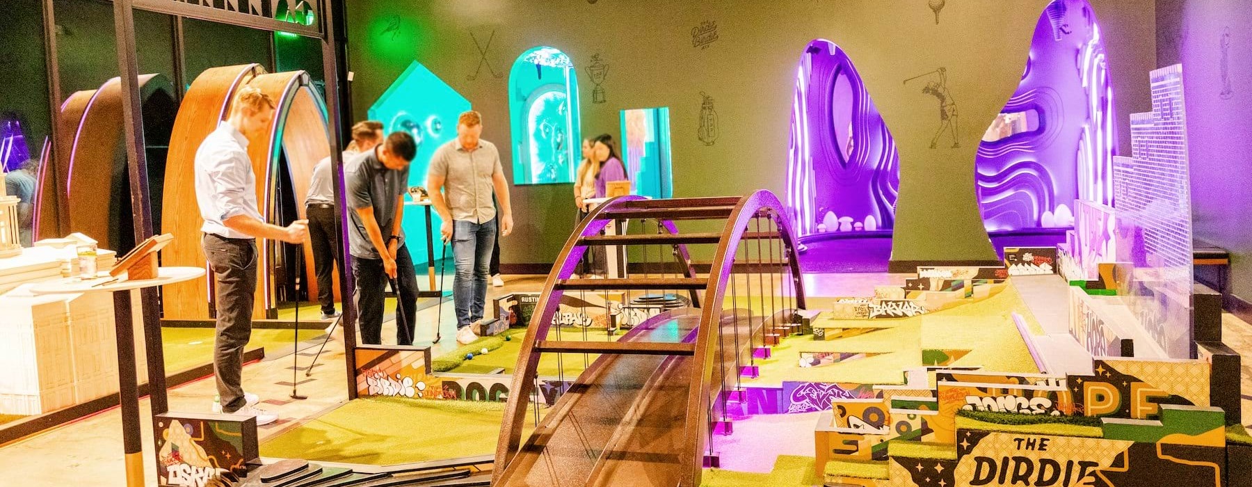 a group of people playing miniature golf inside