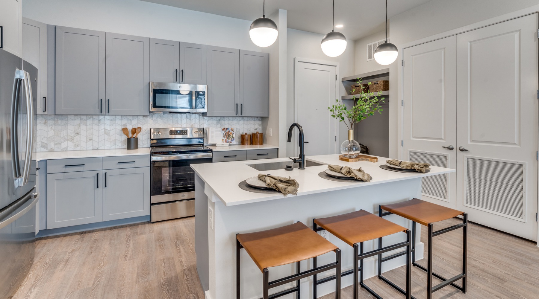 A modern kitchen at The Met apartments in Austin, TX, featuring upgraded stainless steel appliances, cabinets, and a kitchen island with sink and bar seating.