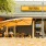 a restaurant with a yellow sign above the entrance and a patio with umbrellas