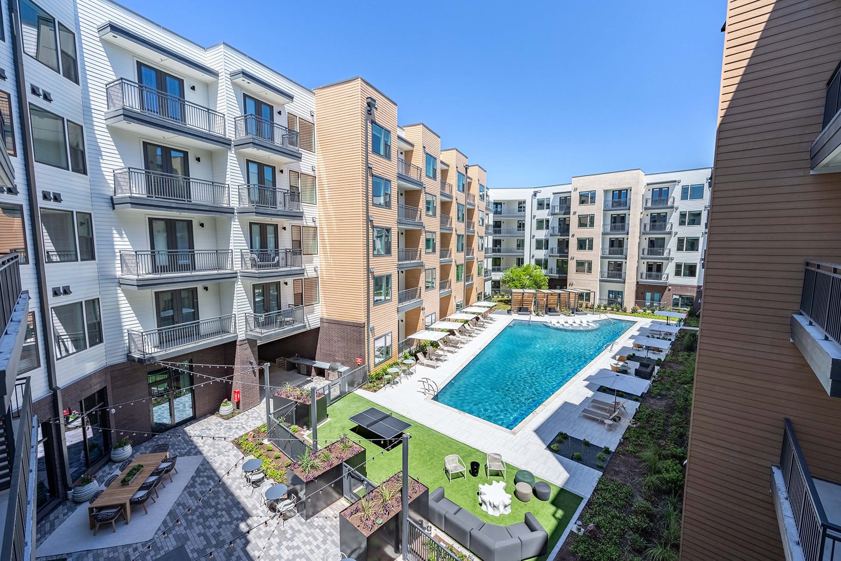 Outdoor Amenities A view of the courtyard, cabana, and resort-style pool and surrounding apartment windows and balconies at The Met in Austin, TX.